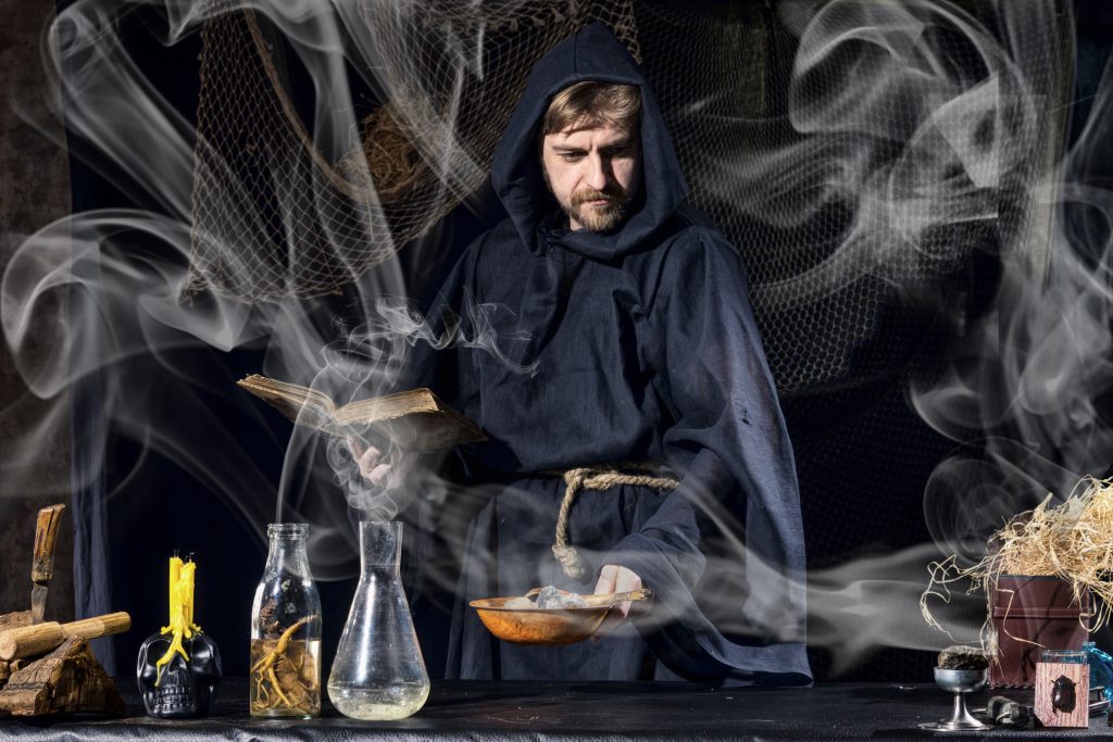 術・Halloween magician is preparing for a magical ritual in ancient table