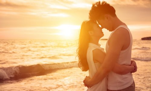 愛young couple kissing at sunset on beach