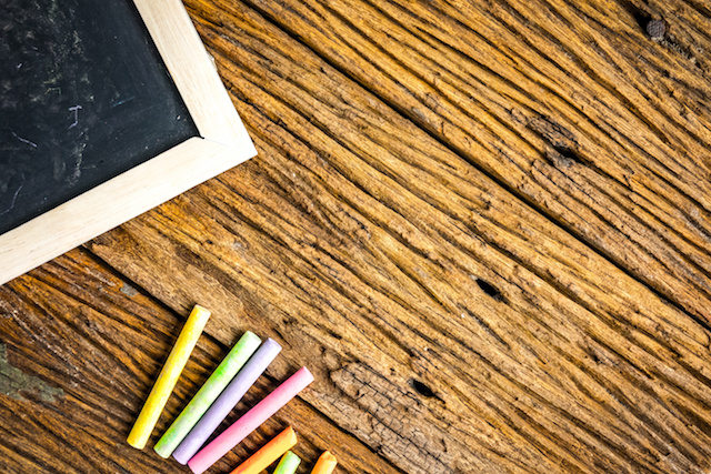 Chalkboard on rough wooden table suface with colorful chalk. Concept for education and businese.