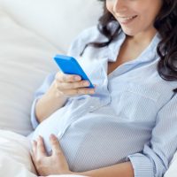 愛・現象・妊娠してる女性close up of pregnant woman with smartphone in bed