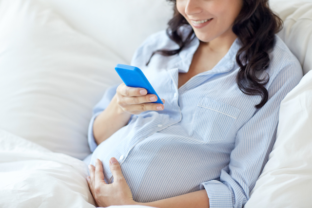 愛・現象・妊娠してる女性close up of pregnant woman with smartphone in bed